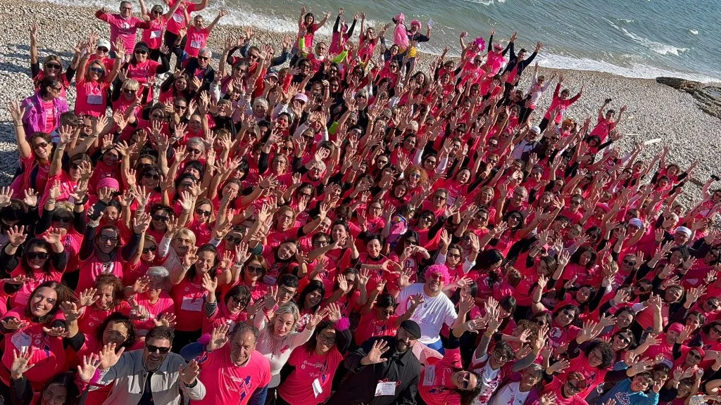 Partecipanti in maglia rosa riuniti sulla spiaggia della Costa dei Trabocchi